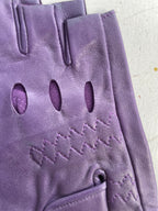 A close-up of an Ines Vintage - Fingerless Fashion Leather Driving Glove by Ines Gloves, showing a detailed view of its stitching and perforations. The glove has three oval ventilation holes and zigzag stitching design near the knuckles. The texture of the leather appears smooth, and the stitching is neat and precise. The background is a flat, neutral surface.