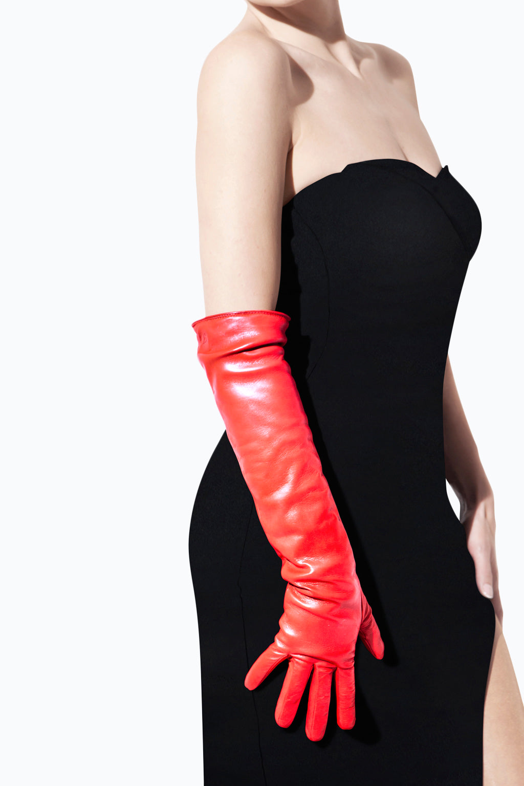 A person wearing a strapless black dress is posing with their left hand on their hip. They are also wearing Ines Gloves long cashmere lined gloves that reach above the elbow. The background is plain white, making the outfit stand out distinctly.